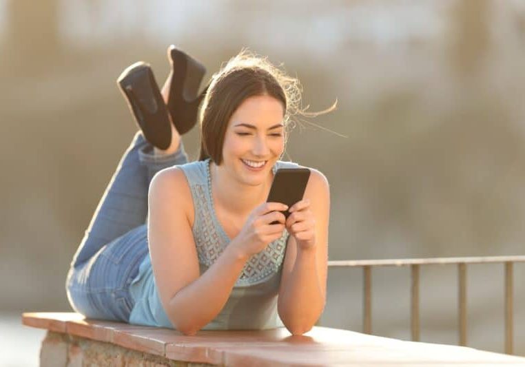 Young woman enjoying reading quality content on her smartphone